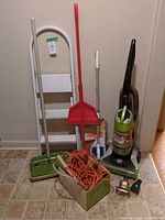 Group shot showing vacuum, ladder, carpet sweeper, dustpan with broom, extension cord box, vacuum bags, nozzle
