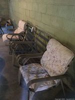 row of four metal patio chairs with two cushions