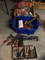 Overall view of blue tote filled with hand tools, yellow tote behind with packaged hardware, hardware tray and loose tools on floor