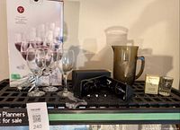 Group shot of wine glass box, loose wine glasses, corkscrew, sunglasses in case, amber pitcher, Seagram’s shot glass
