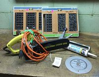 Overview of chainsaw, saw blade, caulk tube, and boxed floor register covers