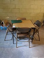 Full view of folding card table with four chairs and green cover on top