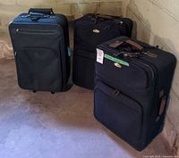 Three suitcases standing upright showing fronts, wheels and handles