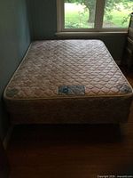 Full mattress on box spring against wall under window