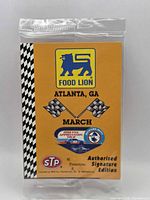 Front view of sealed promotional card showing Food Lion logo, Atlanta GA March text, checkered flags, Richard Petty tour emblem and STP logo