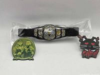 Front view of AEW belt and two enamel pins