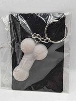 Front view of white bone-shaped keychain on black card in sealed bag