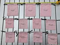 All 12 pink Kate Spade drawstring dust bags laid out with tape measure for scale