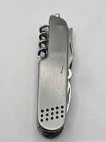 Closed view of multi-tool showing brushed finish, perforated handle end, key ring and corkscrew