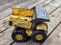 Left side view of Tonka yellow dump truck showing wear and rust