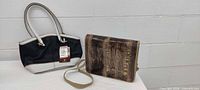 Both bags standing upright on table against wall