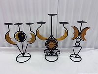 Front view of all three black metal candle holders showing wood sun and moon accents