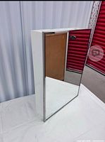 Full view of white metal mirrored medicine cabinet standing upright