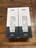 Two boxed Cintas Signature Series soap dispensers on wooden surface