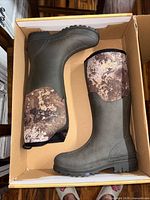 Pair of boots inside box, side view showing rubber lower and camo upper