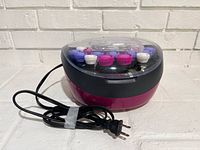 Overall view of Remington heated curler unit with cord and rollers visible under lid