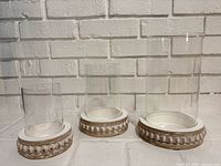 All three glass and white wood candle holders shown together