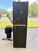 Front view of tall metal cabinet showing door, latch and overall wear