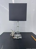 Full view of lamp showing clear glass base and black square shade