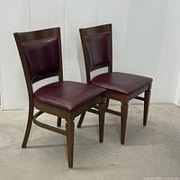 Two matching dining chairs angled side by side displaying frames, upholstery and finish