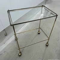 Overall view showing brass-tone frame, glass top, casters