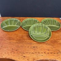 Four olive green divided plates displayed tabletop