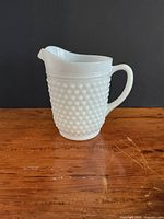 Front view of white milk glass hobnail pitcher