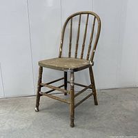 Three-quarter view of wooden spindle-back chair showing hoop back, seat, legs and stretcher