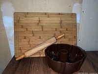 Cutting board upright, rolling pin resting diagonally, Bundt pan front on table