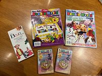 Front covers of two Beanie World magazines, Bean Family Pocket Guide, two sealed tag protector packs