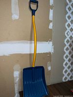 Full view of snow shovel leaning against wall