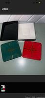 Two ceramic dishes, one red, one green, gold bow design, shown with black box and foam insert