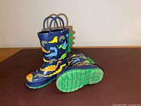 Both boots upright and on side showing dinosaur print and handles