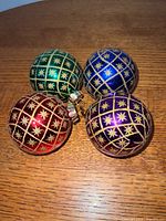 Group shot of four coloured Radko baubles on wood surface