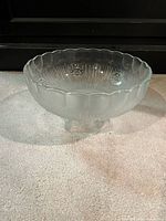 Side view of pressed glass compote showing scalloped rim and pedestal foot