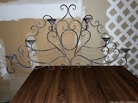 Full view of wrought iron wall candle holder showing five arms and scrollwork