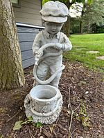 Full view of concrete boy statue with hose and planter