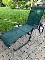 Side view of green metal mesh chaise lounge on patio
