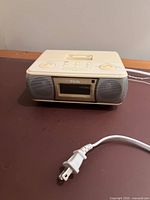 Front view of iMode ivory alarm clock radio showing display, speaker grilles and AC cord