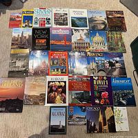 Single image showing all 32 paperback travel guidebooks laid out on carpet, covers visible