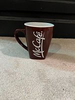 Full view of McCafé mug standing on carpet