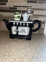 Full view of stove-shaped teapot with condiment set on top