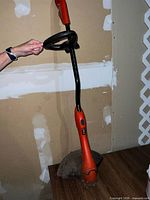 Full view of orange corded string trimmer held upright