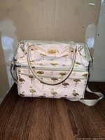 Front view showing flamingo print, front zip pocket, shoulder strap
