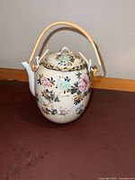 Full view of teapot showing floral design, bamboo handle and overall form
