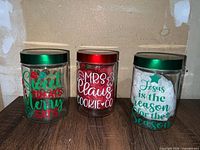 Three glass canisters side by side showing lids and decals