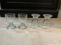 Four clear glass ribbed egg cups standing upright and inverted