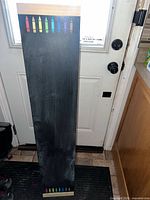 Front view of tall chalkboard showing wood frame, black writing surface, crayon motif