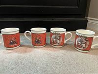 All four mugs front view showing rabbit family with wreath border on red background