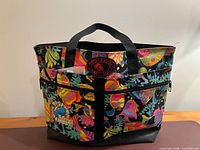 Front view showing tropical print, Maui patch, exterior zip pocket, dual handles